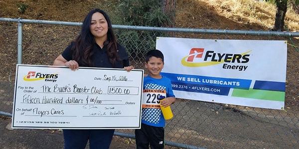 Image of Flyers employee with large check for $1500 being presented to a charity.