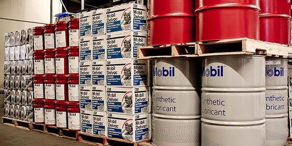 Warehouse image showcasing pallets of Mobil lubricant boxes and drums